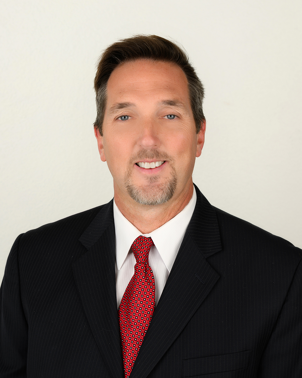 Man smiling with black suit coat and red tie