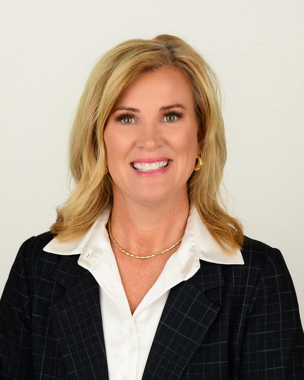 Woman smiling with blonde hair, black jacket, white shirt