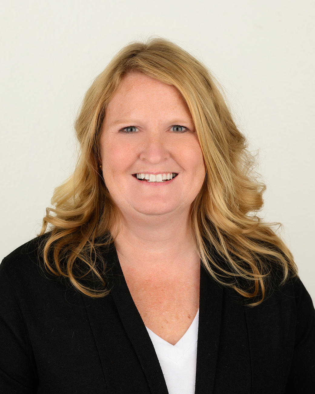 Woman smiling with black suit jacket and blonde hair